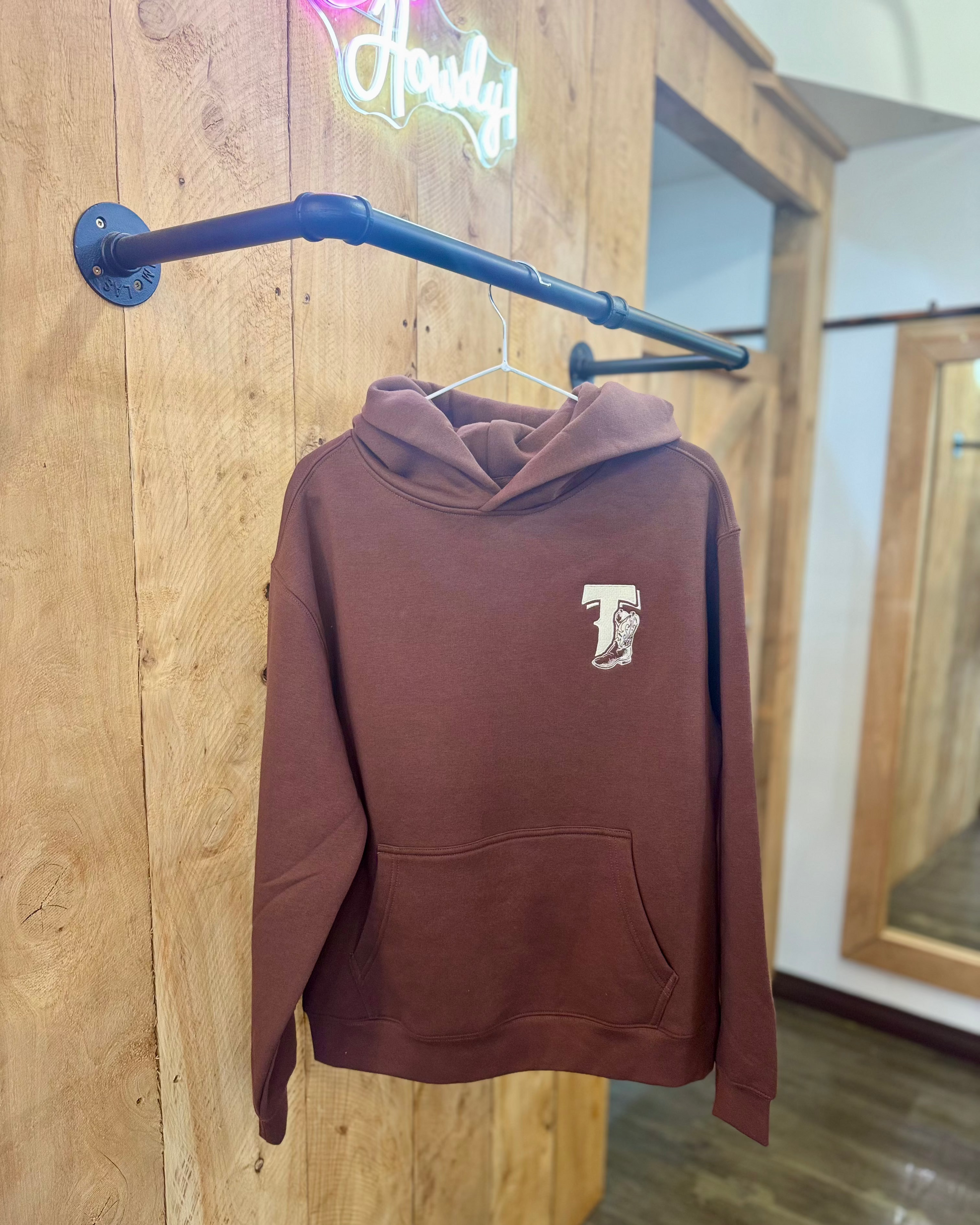 Chestnut Brown Texas Western Apparel hoodie with intricate embroidery. The front features a detailed embroidered 'T' and a Western-style boot, while the back showcases the Texas Western Apparel logo. A bold and stylish statement piece with a classic country flair.